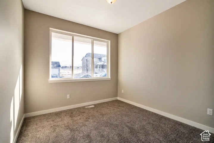 Neutral-toned wall finishes with a large multi-pane window, flush-mount ceiling light, and carpet flooring