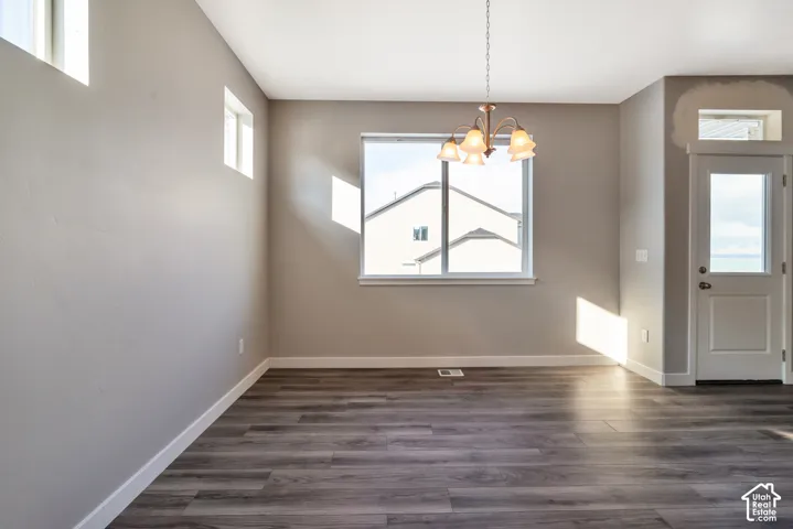 Wood-finish flooring, multiple windows, a ceiling-mounted light fixture, and a glass-paneled door