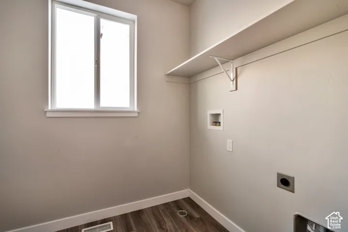 Utility room with wood-finish flooring, a white-framed window, and a wall-mounted shelf