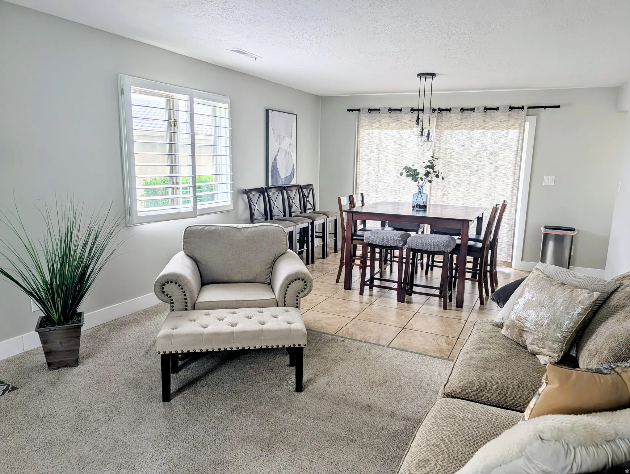 Carpeted living area with a large window featuring plantation shutters