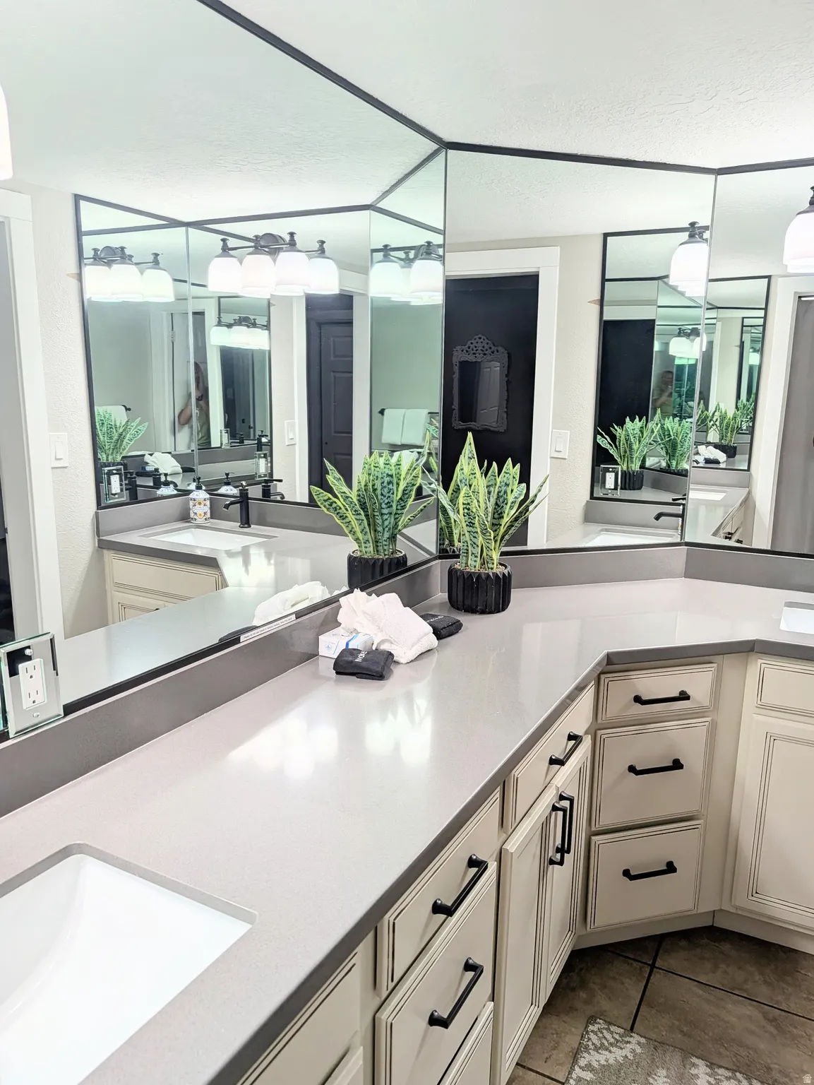 Double vanity with light-toned countertops, integrated sinks, and lower cabinetry featuring black hardware