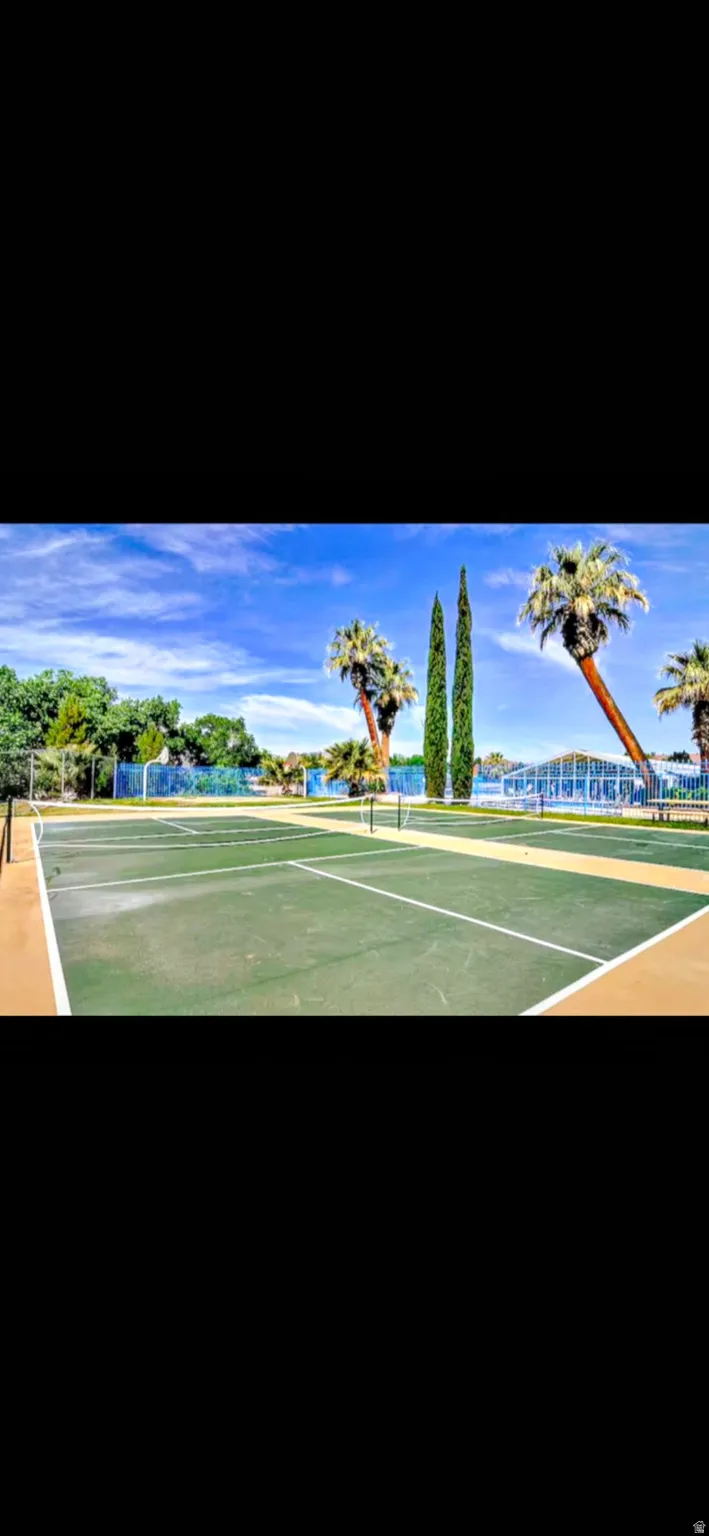 Multiple tennis courts with green playing surfaces, marked with white lines, and bordered by tan perimeters