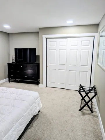 Wall-to-wall carpeting with white trim, recessed square lighting, and white sliding closet doors