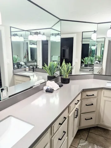 Double vanity with light-toned countertops, integrated sinks, and lower cabinetry featuring black hardware
