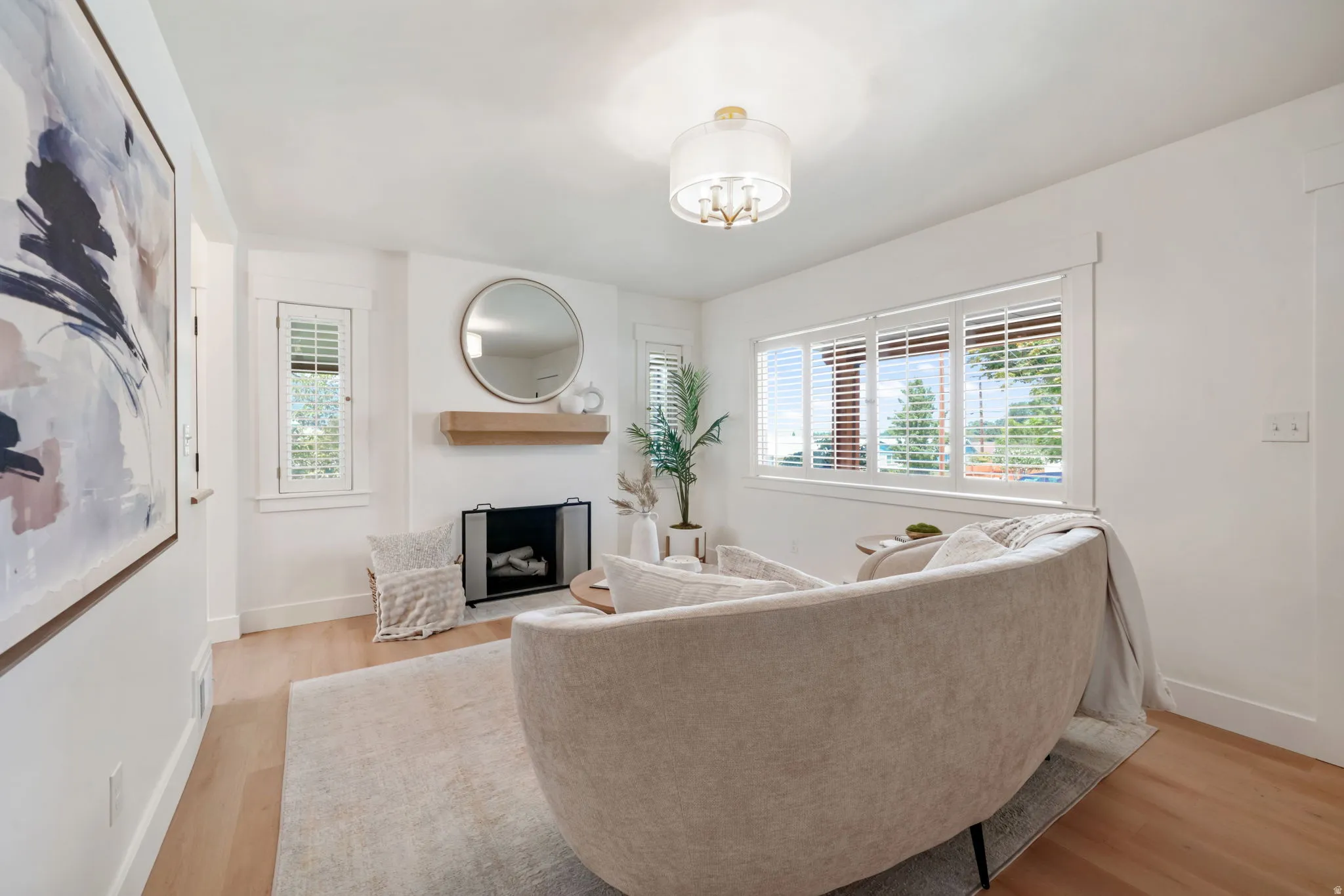 Recessed fireplace with a wood-finish mantle, wood-finish flooring, and white plantation shutters