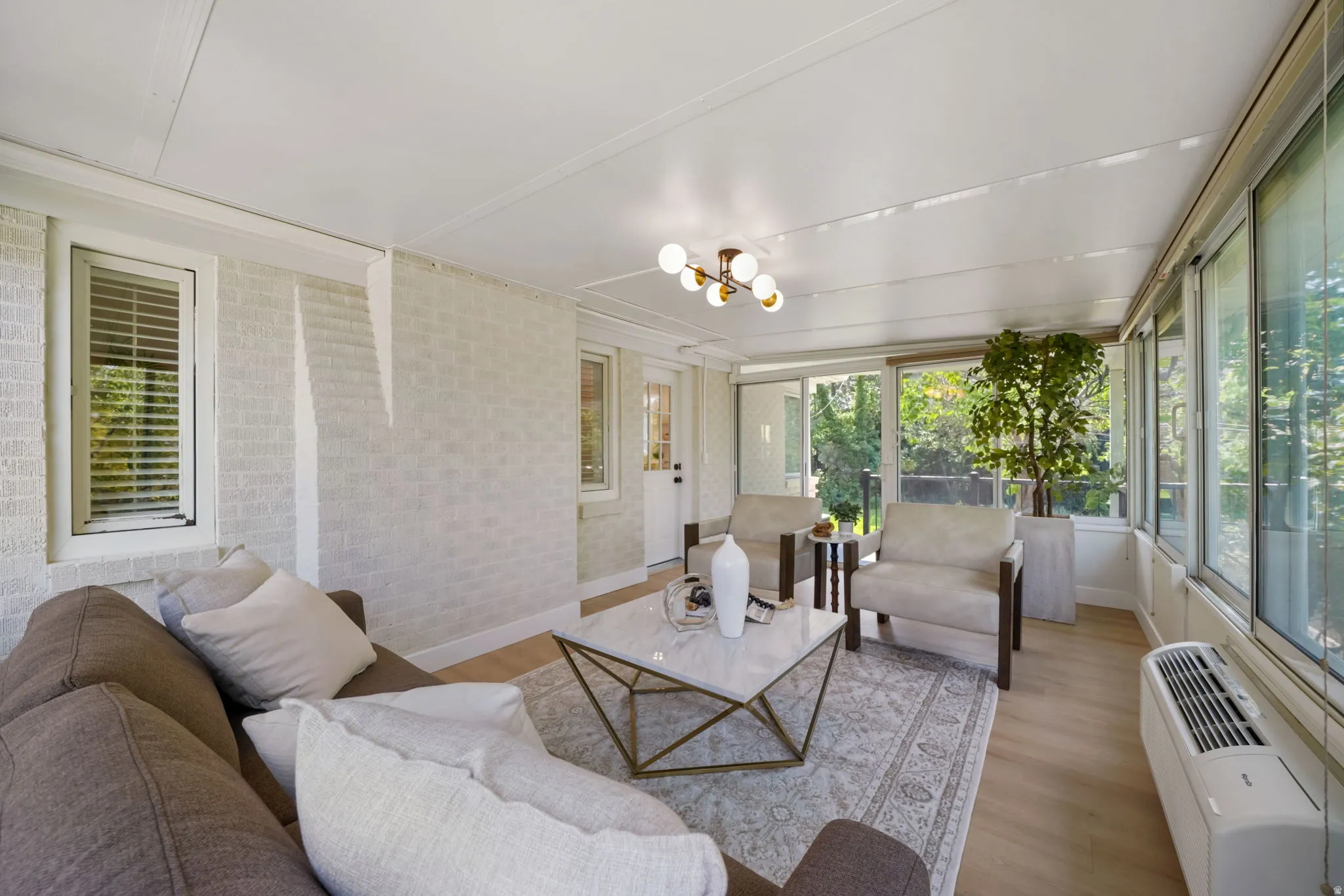 Sunroom with abundant natural light, light wood-finish flooring, white paneled ceiling, and a contemporary ceiling light fixture