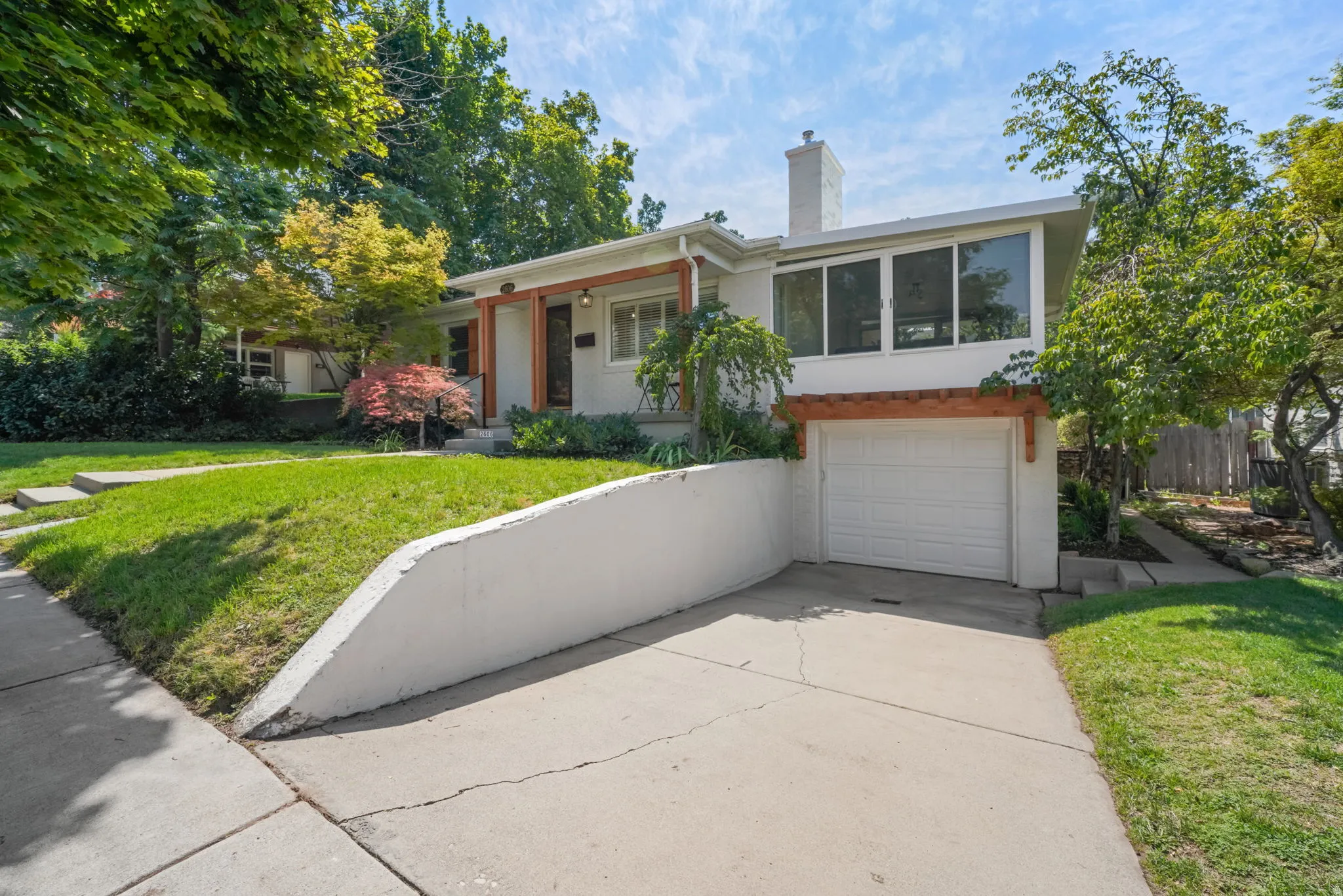 Split-level residence featuring a white stucco exterior, integrated garage with a white door, and a prominent chimney