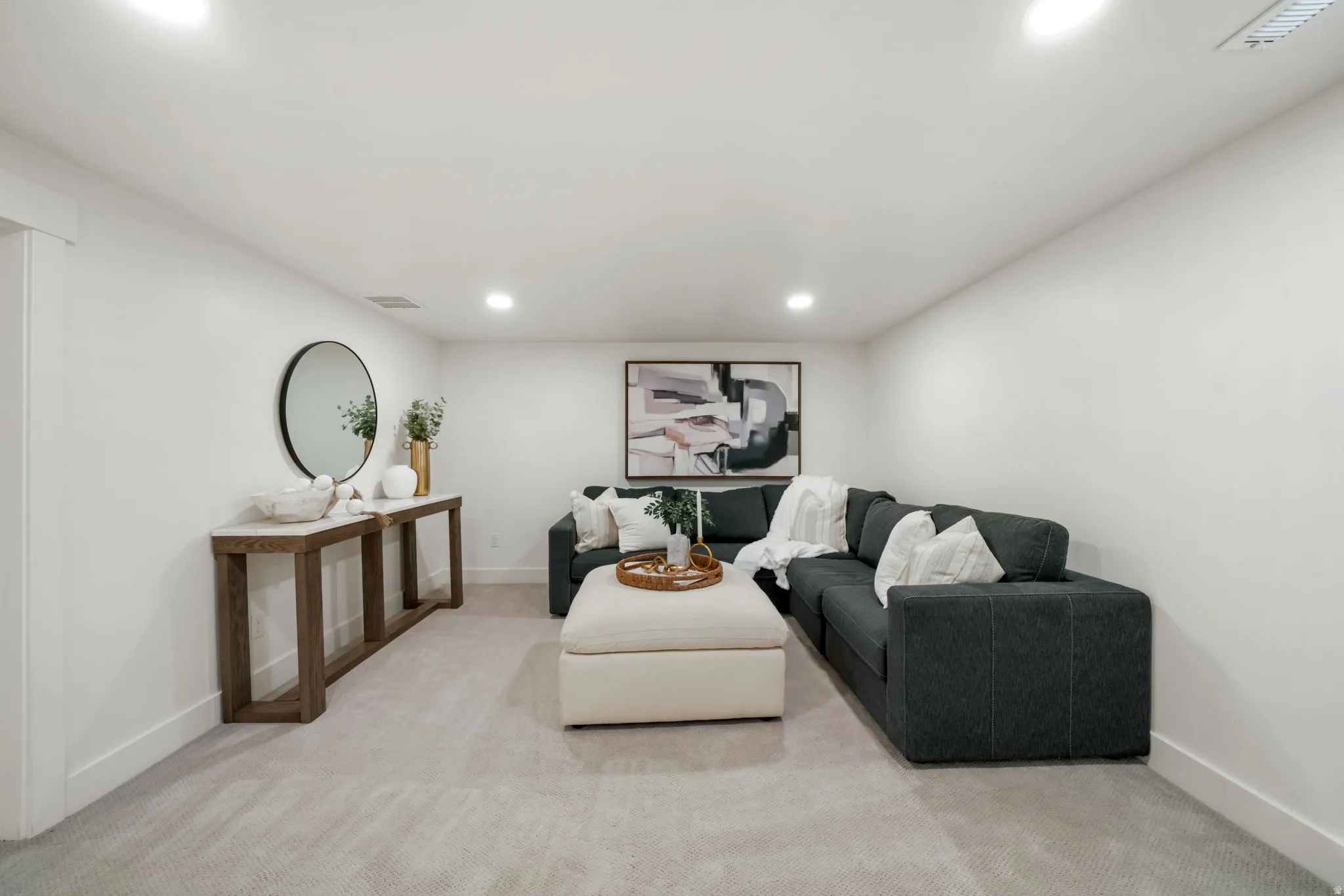 Recessed lighting, wall-to-wall carpeting, and a console table with a stone top