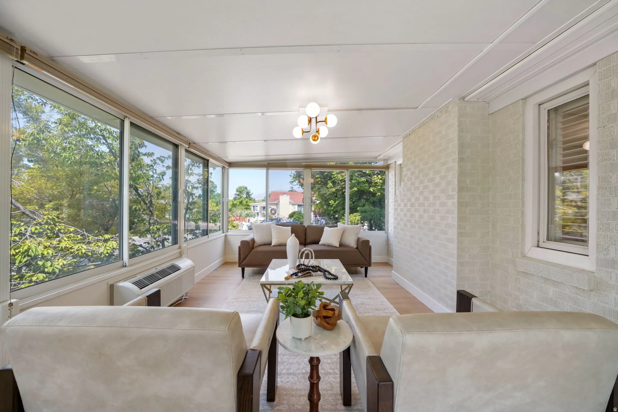 Sun-drenched room featuring a wall of expansive windows, light wood-finish flooring, and a contemporary ceiling light fixture