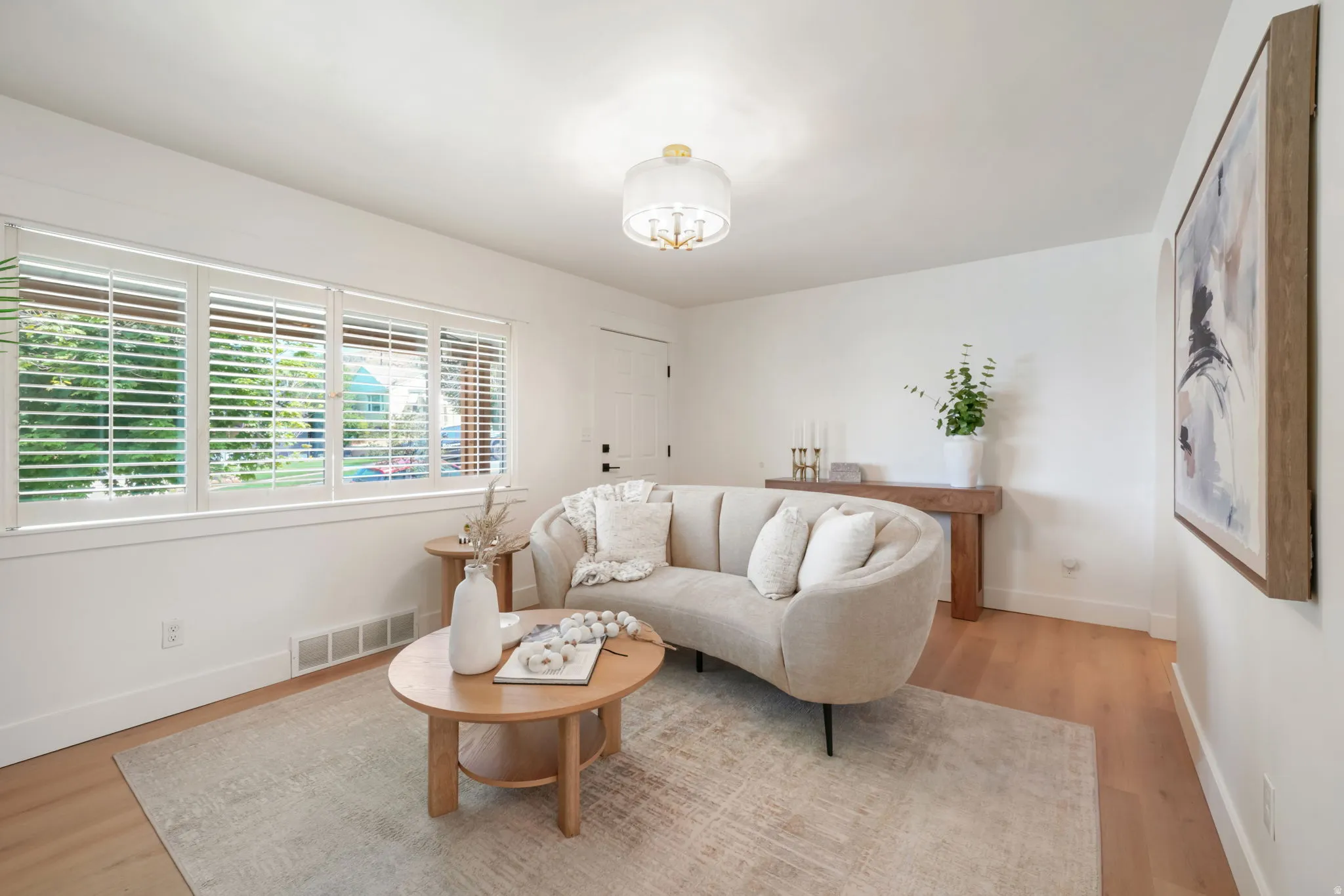 Recessed lighting, wood-finish flooring, white walls, multiple windows with blinds, and a built-in wall-mounted light fixture