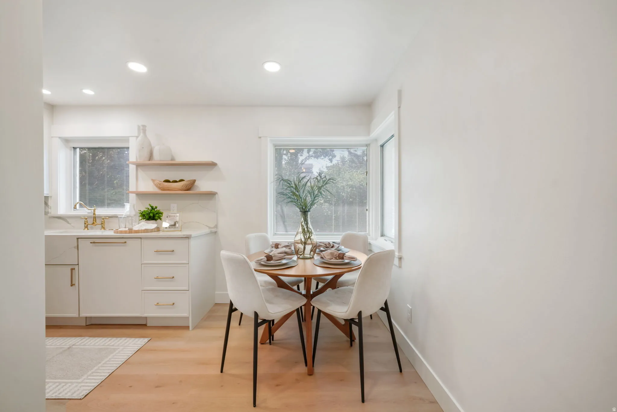 Recessed lighting, wood-finish flooring, white cabinetry, integrated farmhouse sink, and open shelving