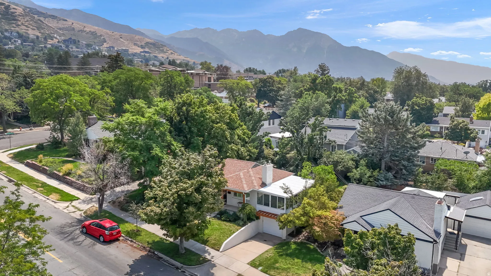 Charming residence nestled in a tree-lined neighborhood with mature landscaping and mountain backdrop