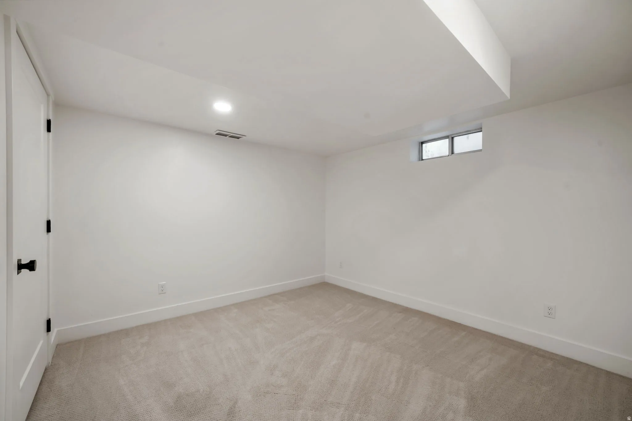 Carpeted flooring, recessed lighting, and a white interior door with black hardware