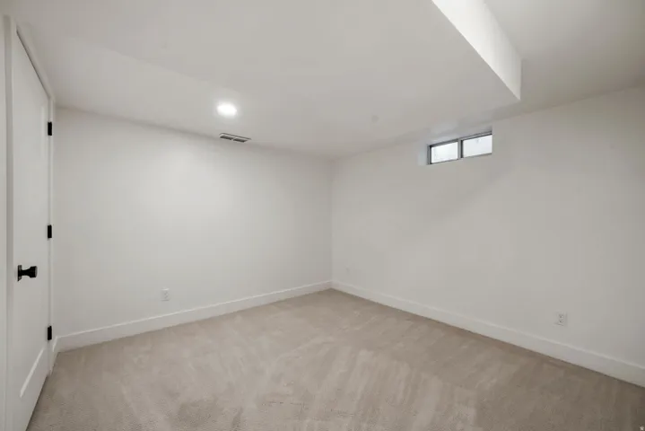 Carpeted flooring, recessed lighting, and a white interior door with black hardware