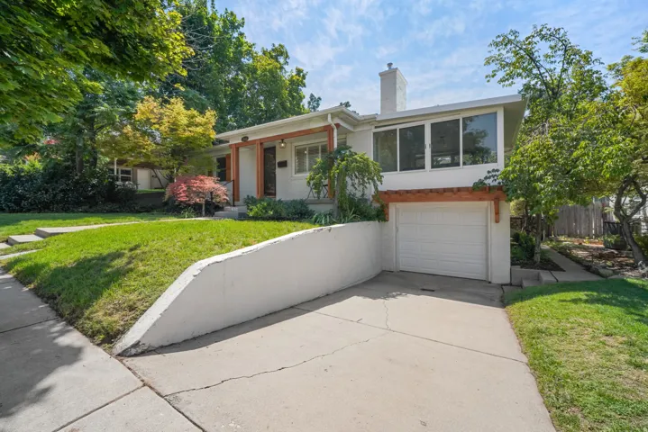 Split-level residence featuring a white stucco exterior, integrated garage with a white door, and a prominent chimney