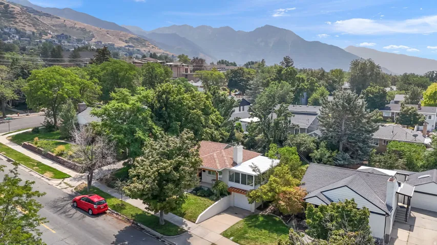 Charming residence nestled in a tree-lined neighborhood with mature landscaping and mountain backdrop