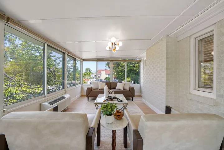 Sun-drenched room featuring a wall of expansive windows, light wood-finish flooring, and a contemporary ceiling light fixture
