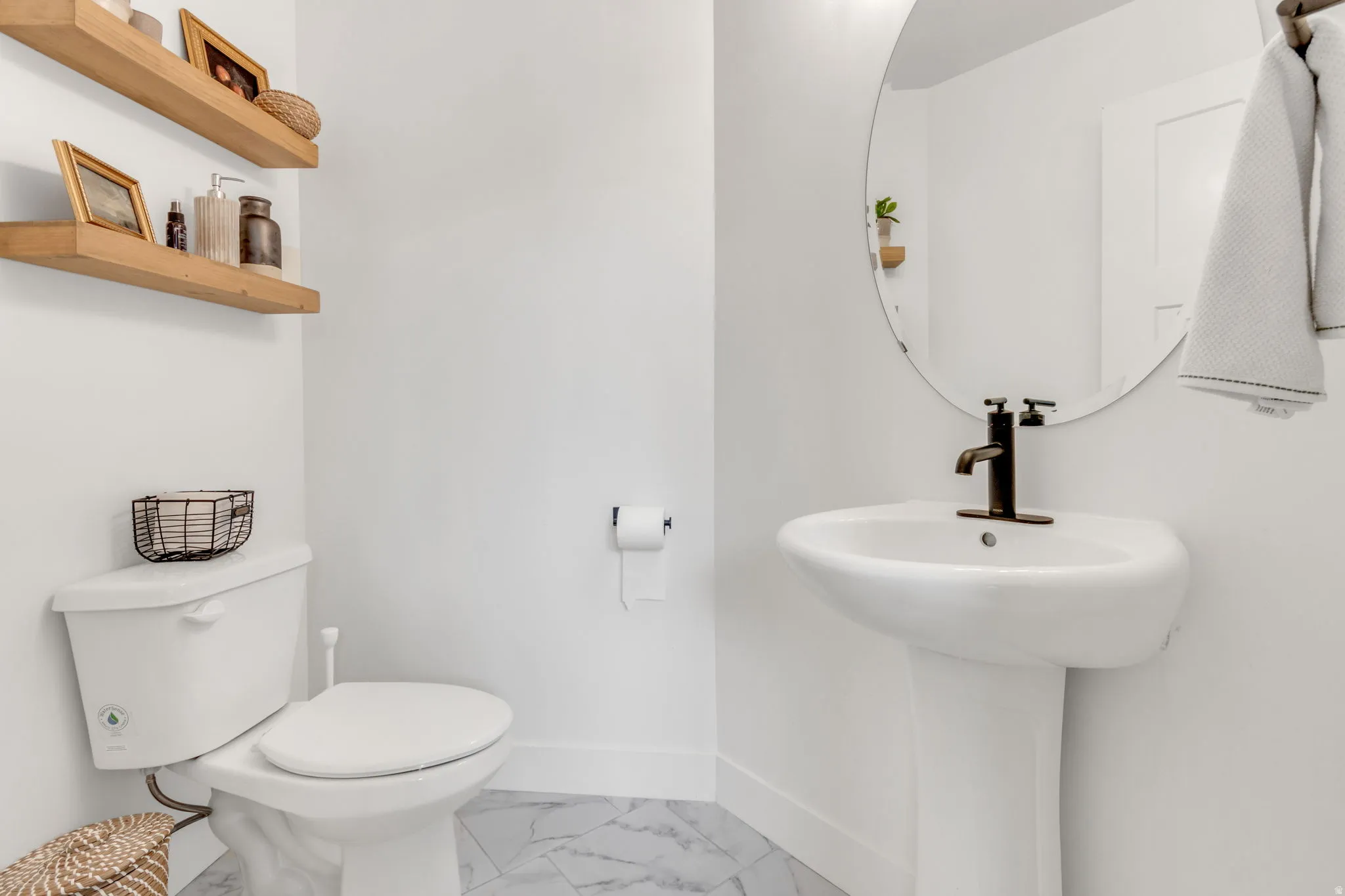 Pedestal sink with matte black hardware and a round mirror