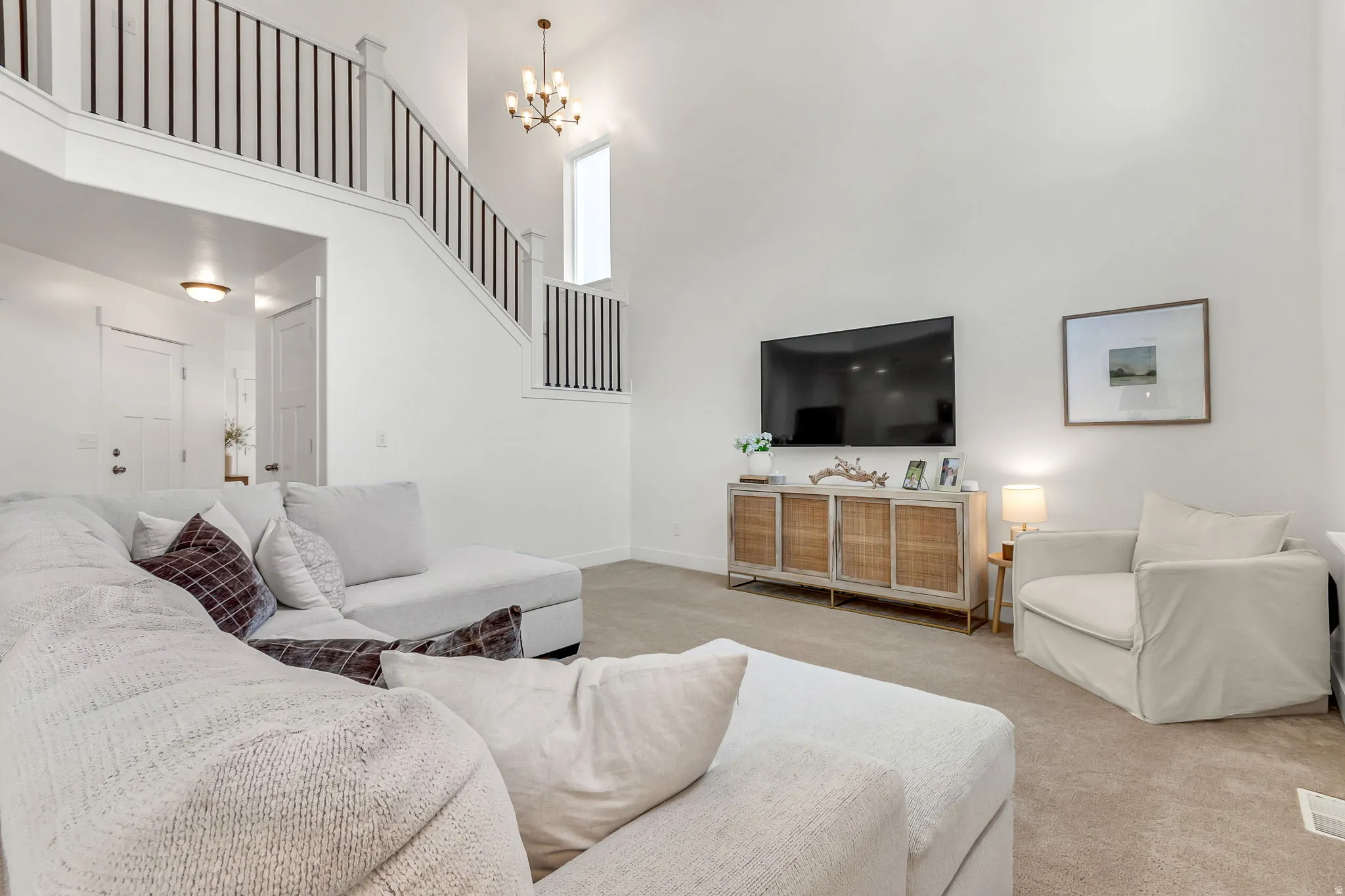 Two-story living area featuring a vaulted ceiling and an open staircase with black iron balusters