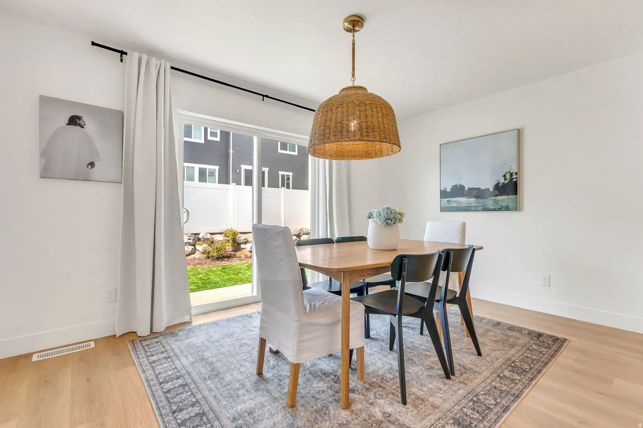 Dining area featuring light wood-finish flooring and a contemporary woven pendant light fixture