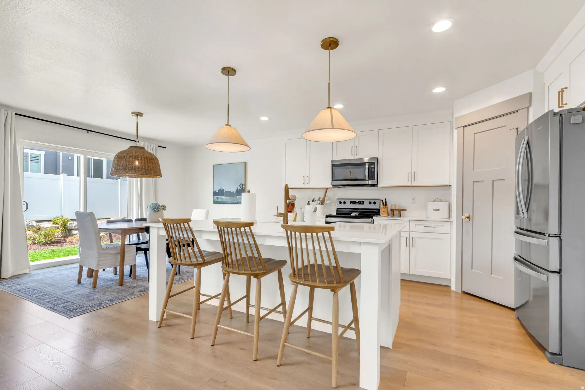 Bright kitchen featuring white cabinetry, a central island with countertop seating, stainless steel appliances, and light wood-finish flooring