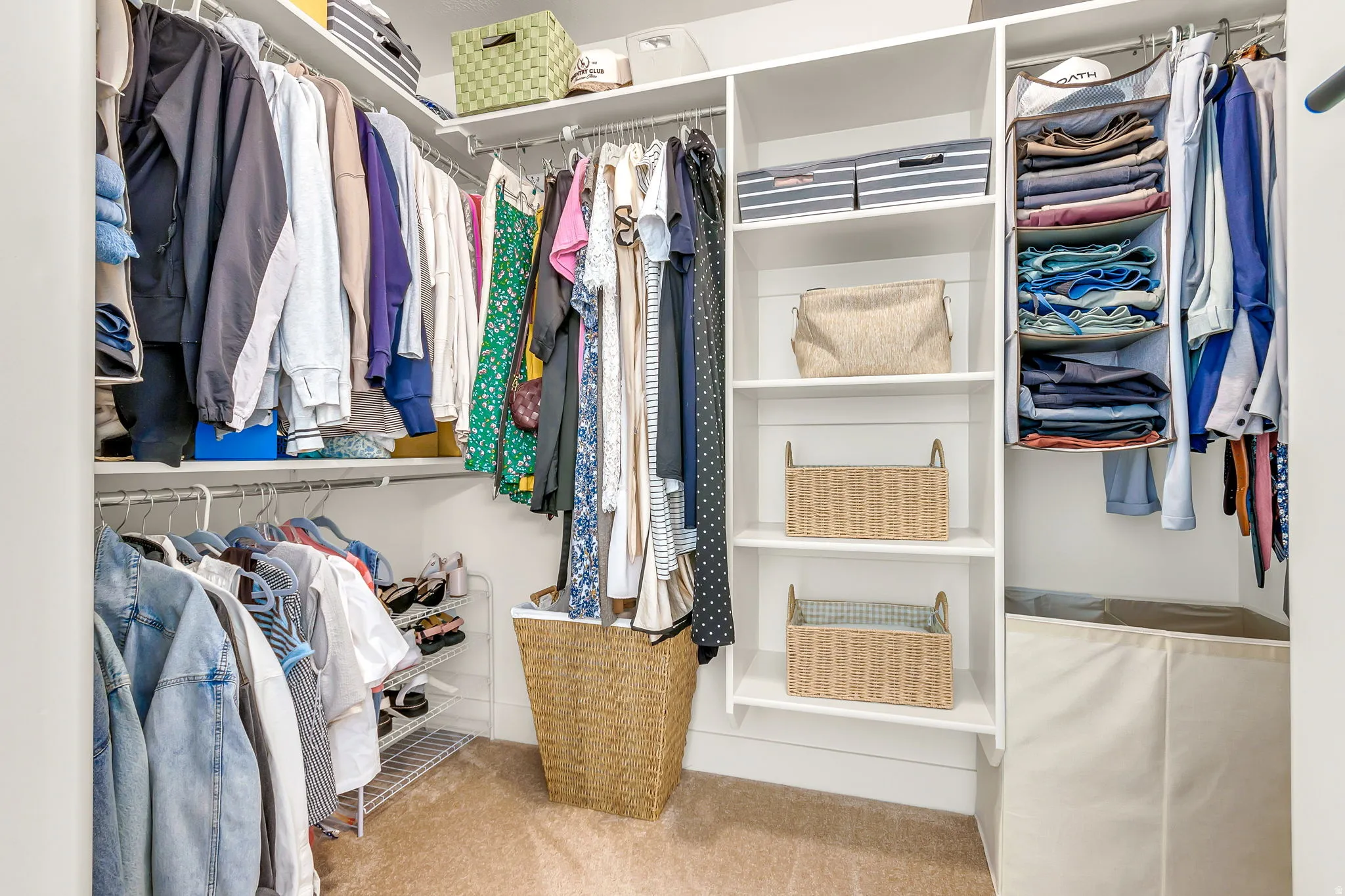 Built-in closet organization system featuring white shelving, multiple hanging rods, and plush carpet flooring