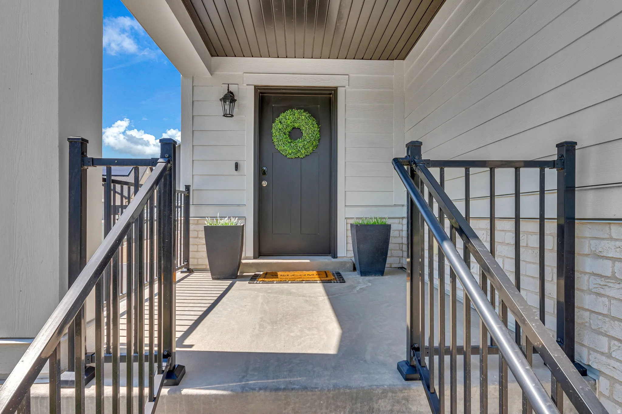 Entry porch with concrete steps and black metal railings