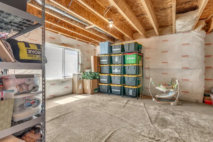 Unfinished basement space featuring exposed wood joists and a single window