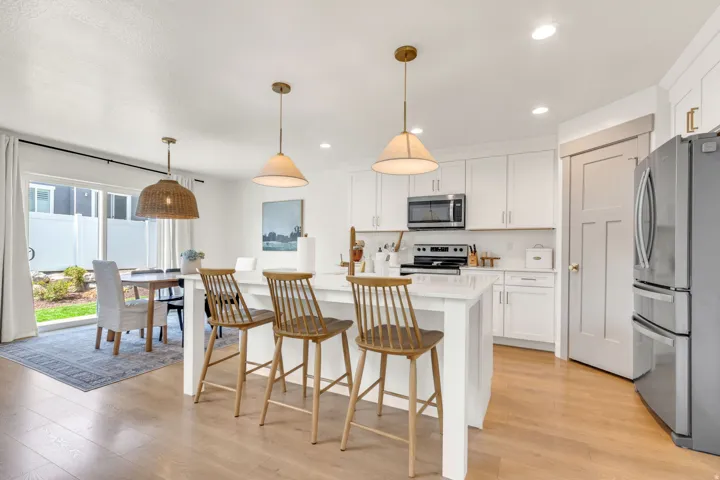 Bright kitchen featuring white cabinetry, a central island with countertop seating, stainless steel appliances, and light wood-finish flooring