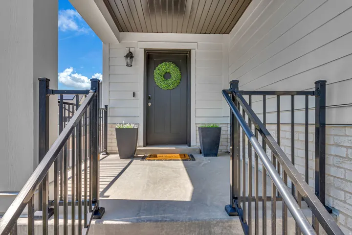 Entry porch with concrete steps and black metal railings