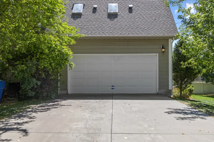 Attached two-car garage featuring a segmented white door and overhead outdoor lighting