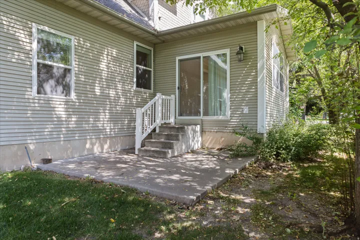 Spacious composite deck and patio area featuring composite decking with a white aluminum railing system, wide entry stairs, and large sliding glass doors providing access to the home's interior