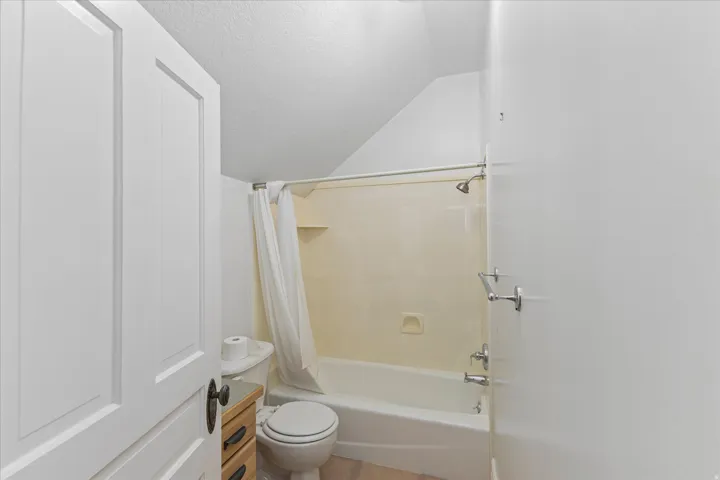 Bathroom featuring a tub/shower combination, white toilet, and wood-finish vanity with drawer storage