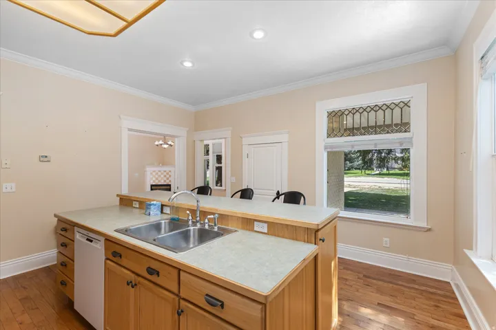 Chef's kitchen featuring a substantial wood-finish island with dual sink and abundant storage, complemented by white cabinetry, light stone countertops, and stainless steel appliances