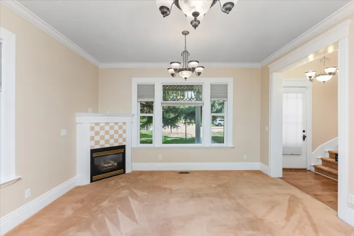 Spacious living room featuring hardwood flooring, a decorative fireplace with checkered tile surround, and large multi-pane windows with natural light
