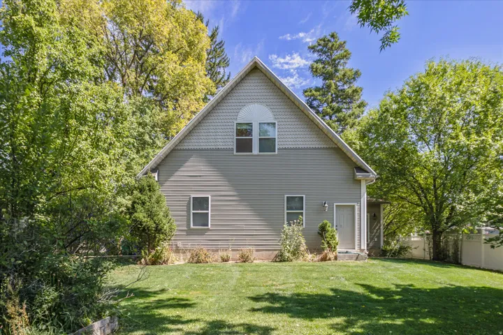 Gable-roofed home with light gray siding, an upper arched window, and a ground-level entry door