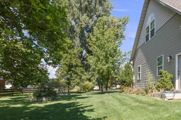 Expansive side yard featuring a manicured lawn, mature trees, and landscaping