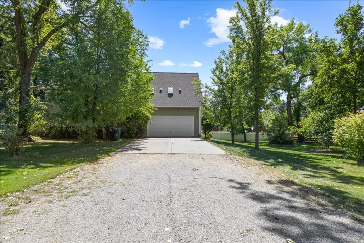 Gravel driveway leading to a two-story residence with light green siding