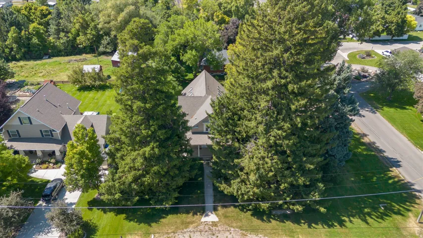 Traditional style residence with a prominent roofline, a front walkway leading to the entry, and mature trees providing natural landscaping