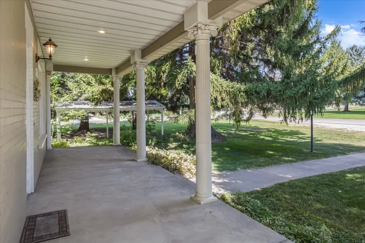 Covered concrete porch featuring fluted columns with ornate capitals