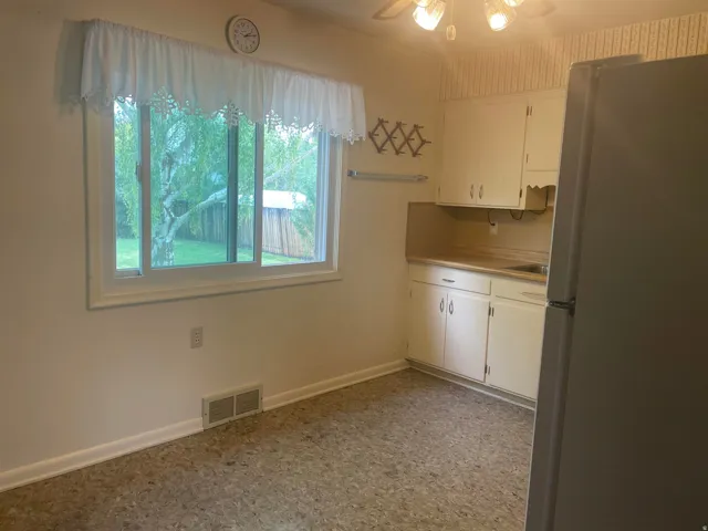 Kitchenette featuring white cabinetry, a single basin sink, and a built-in refrigerator
