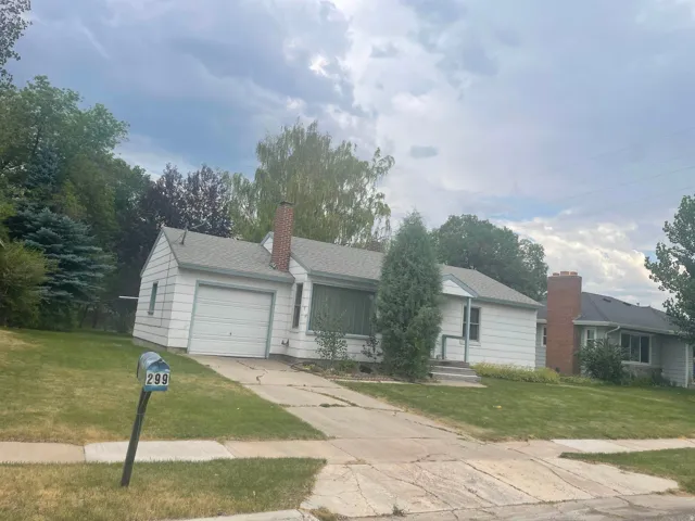 Ranch-style exterior with white siding, an attached garage, and a brick chimney