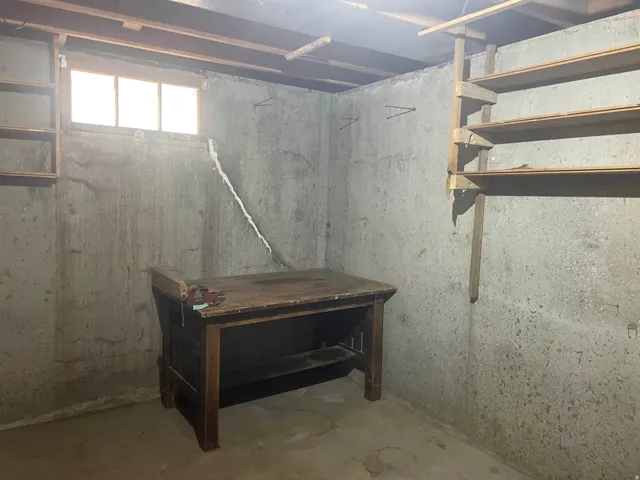 Concrete foundation walls with exposed wood ceiling joists and a single-pane window