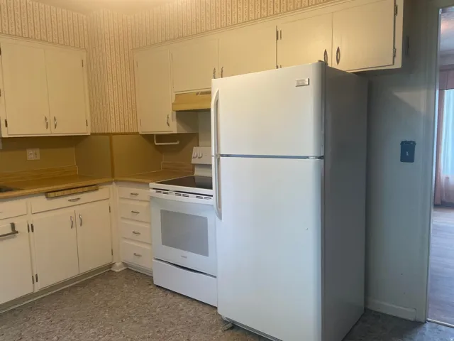 Kitchen featuring white cabinetry with brushed nickel hardware, wood-finish countertops, and a full suite of white appliances