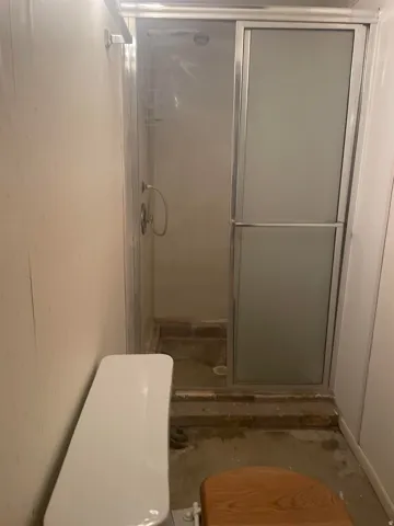 Shower enclosure with sliding frosted glass door, chrome hardware, and white shower surround