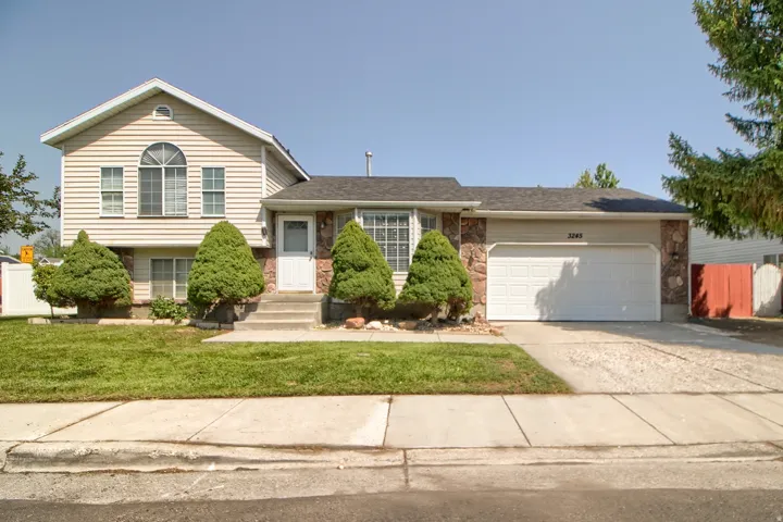Two-car garage with a paved driveway, stone accents, and a front lawn