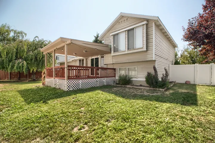 Two-story home with spacious backyard featuring mature landscaping, a covered patio with lattice detailing, composite decking with decorative skirting, and a fully fenced perimeter
