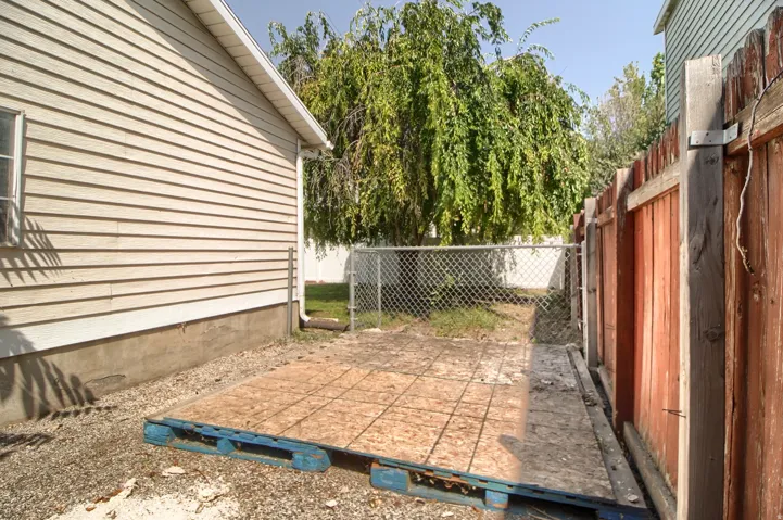 Side exterior featuring horizontal siding, a gravel ground covering, and a wood privacy fence