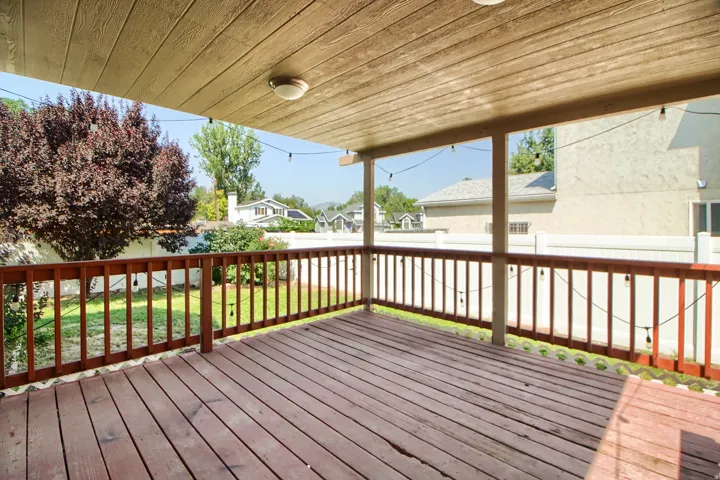 Covered outdoor deck with wood-finish flooring and railing