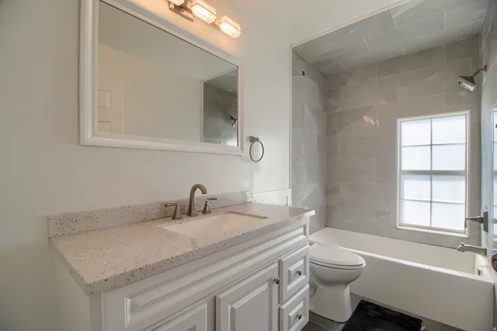 Spa-inspired bathroom featuring a floating vanity with speckled quartz countertop, polished nickel faucet, and generous storage cabinetry